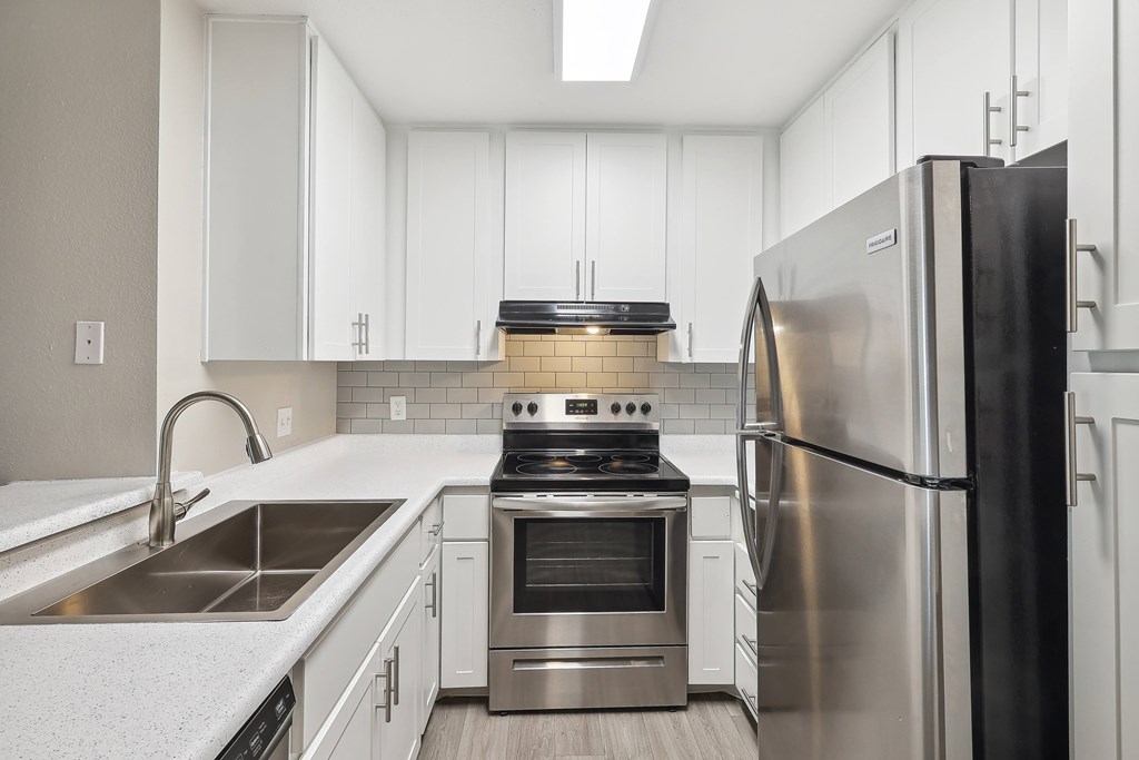 a kitchen with white cabinets and stainless steel appliances